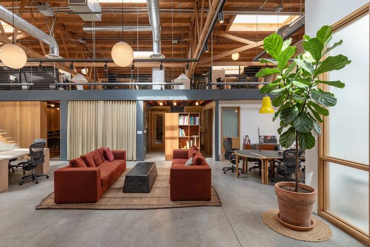 A daylit office lounge with exposed timber trusses, a mezzanine, and custom seating, delivered as part of a brokerage and project management engagement