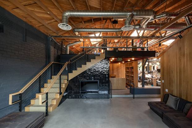 The same space, mezzanine stair and lounge with a black tiled fireplace, after build-out